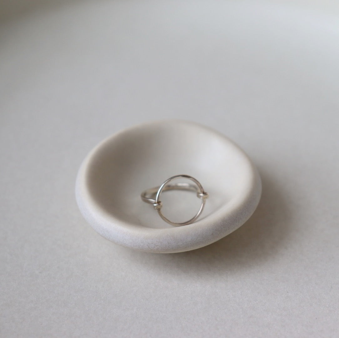 925 Sterling Silver Eternity Ring is sitting on white plate. This ring is features a circle disc that is wrapped with an additional wire as the band. The band is hammered on the disc as well as the band. The jewelry is hypoallergenic and nickel free. Handmade in Eau Claire, Wisconsin.
