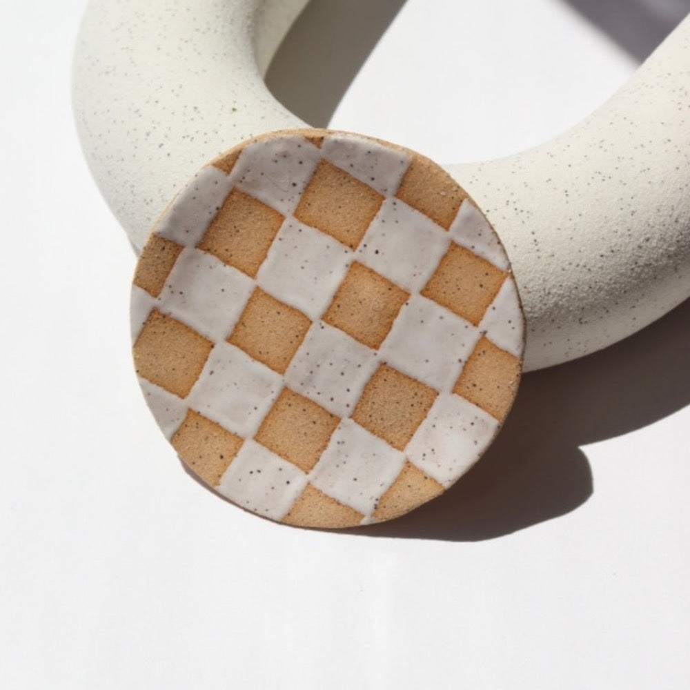 Ceramic Checkered jewelry dish laid against a white jewelry display. This is perfect to sit on your dresser and set your rings on. 