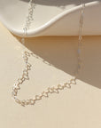 925 Sterling Silver Petite heart chain from Token Jewelry, photographed on a tan, organically shaped dish. This chain features a silver tiny heart wire throughout the whole chain. 