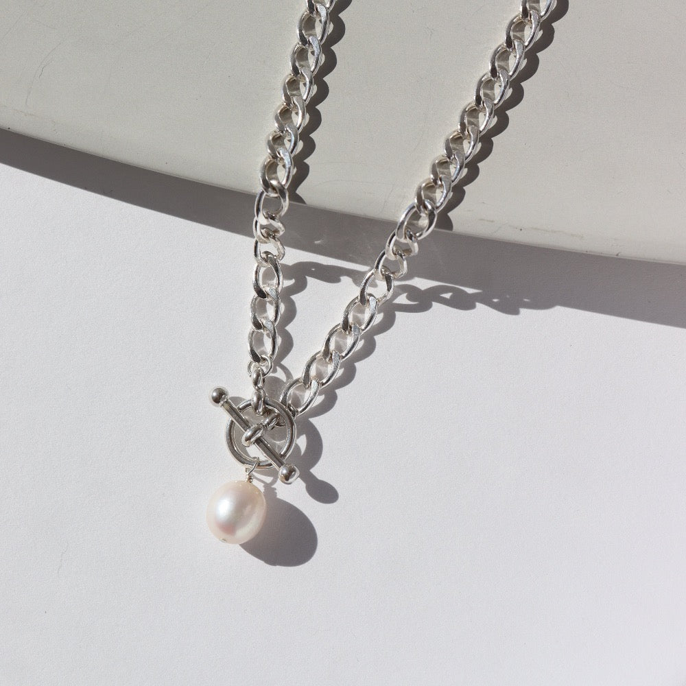 925 sterling silver chain with a toggle clasp and large pearl, photographed on a sunlit tabletop