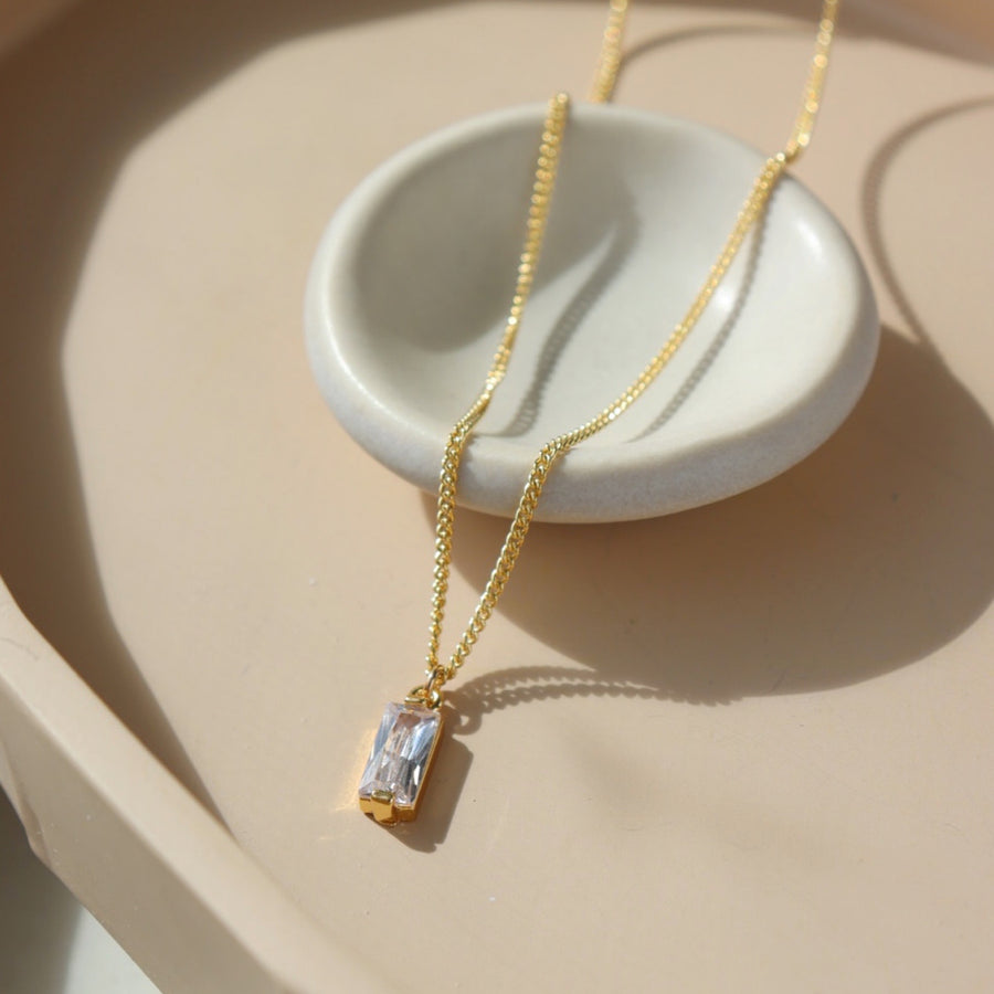 14k gold fill Euphoria Necklace, placed on a white plate on top of a peach colored plate in the sunlight. This necklace is hypoallergenic and nickel free. Handmade in Eau Claire, WI