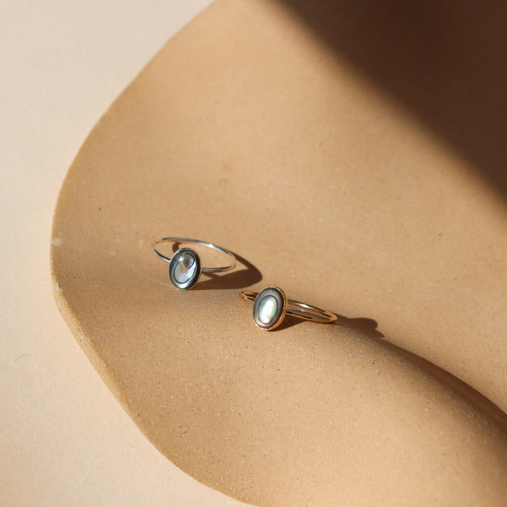 14k gold fill and sterling silver rings with handset abalone stones on a light dish