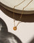 Agate donut shaped gemstone pendant attached to a 14k gold Fill chain in the sunlight