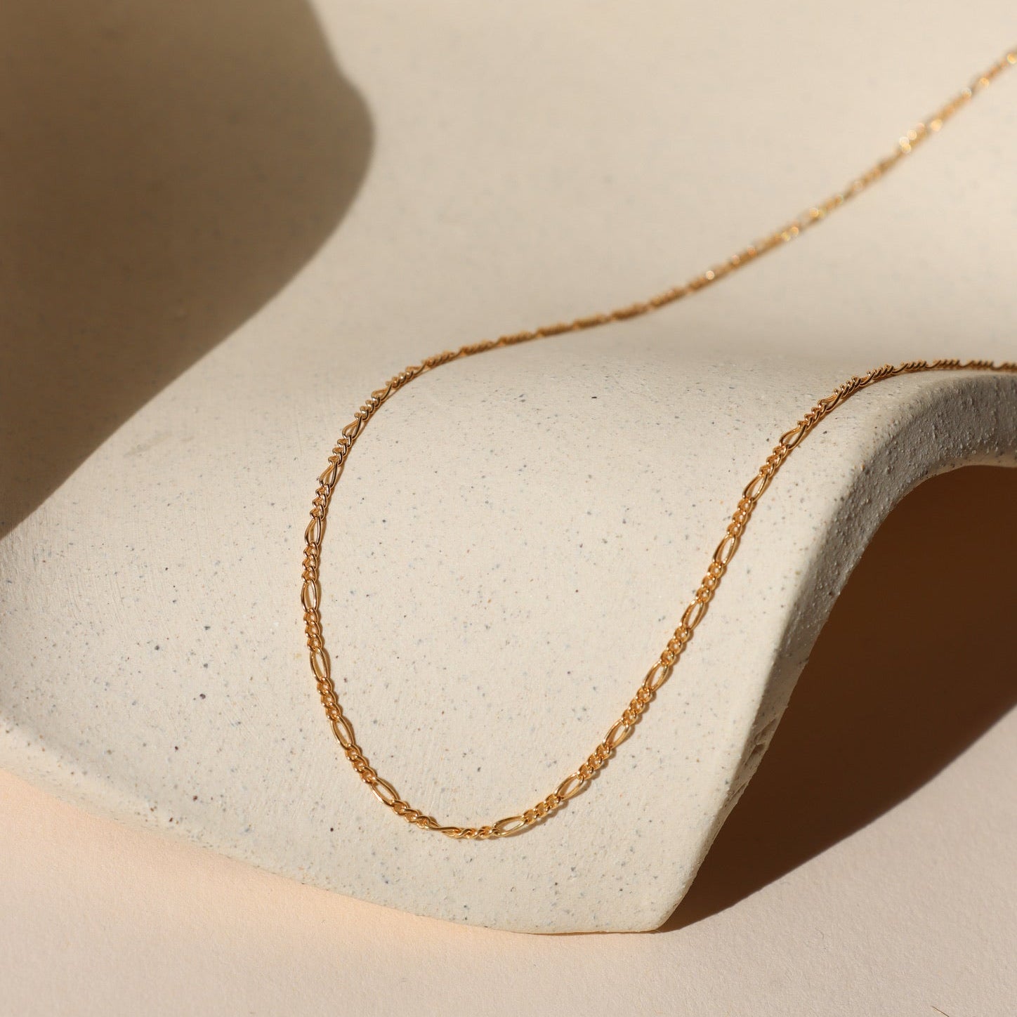 14k gold fill figaro chain necklace on a light dish