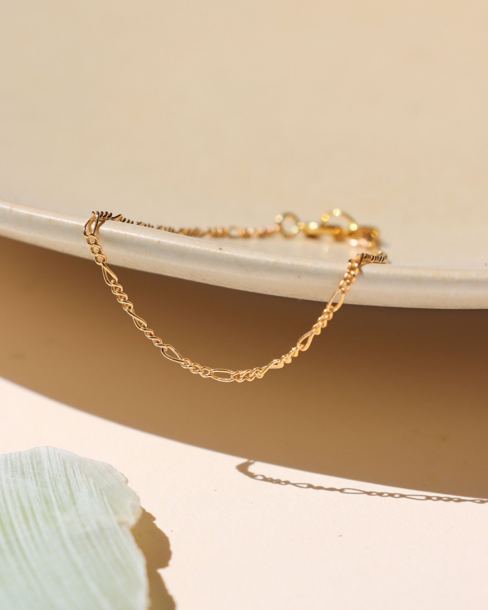 14k gold fill delicate figaro chain bracelet on a light surface