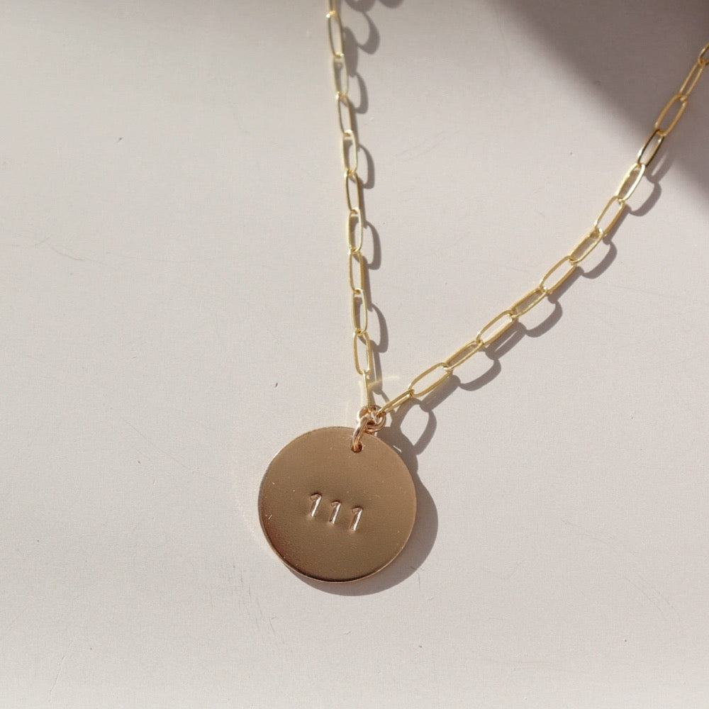 14k gold fill angel number pendant on a gold fill chain, photographed on a ceramic dish