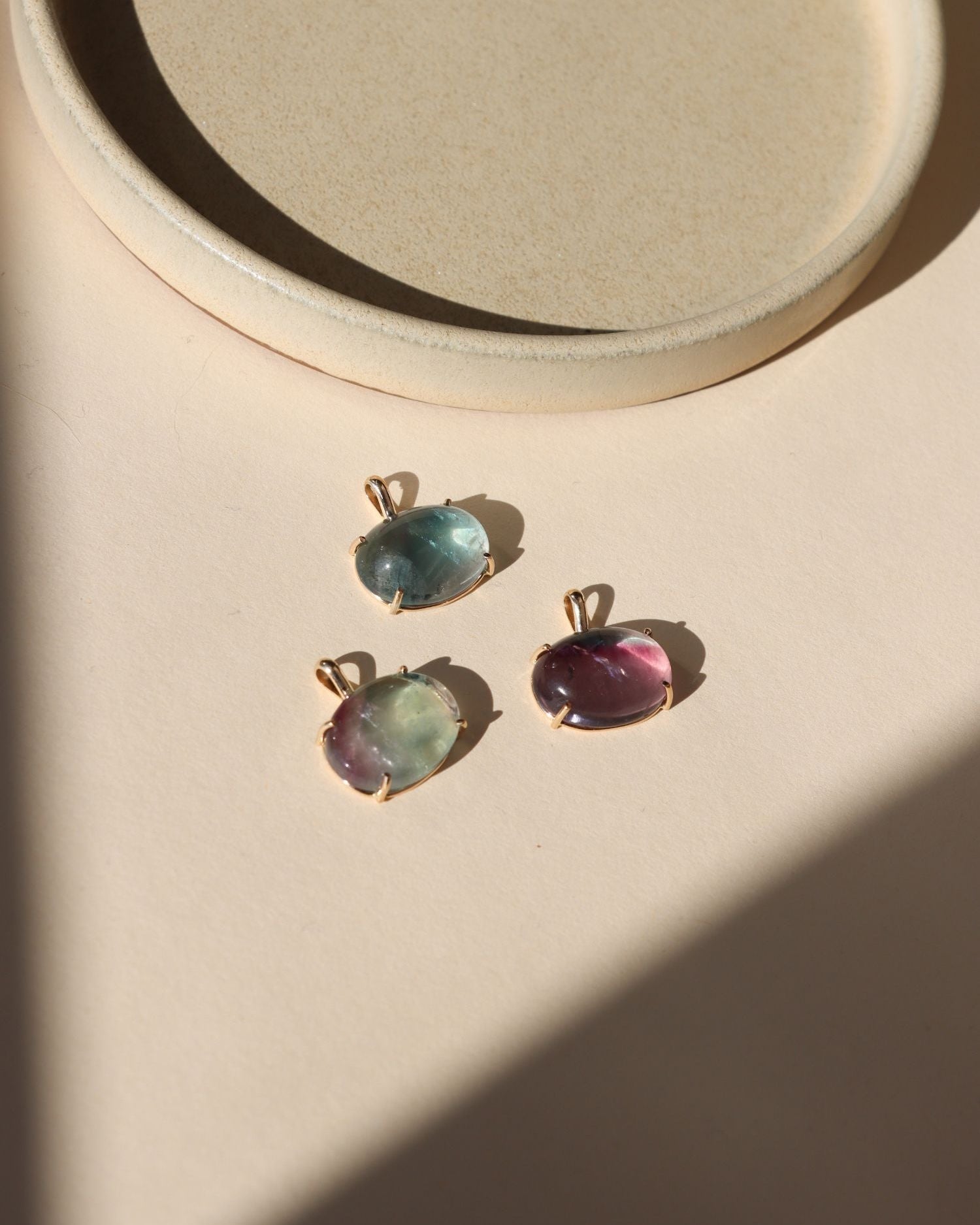 14k gold fill bezel pendants with oval fluorite cabs on a light dish