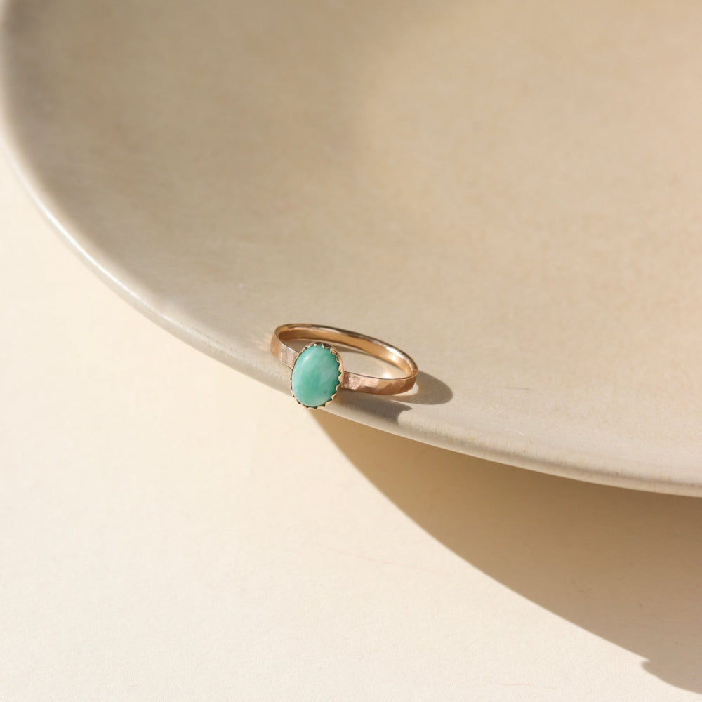 A 6x8mm amazonite gemstone set in a 14k gold fill serrated bezel. The ring is displayed on a cream dish. 