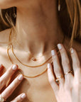 Model wearing 14k gold fill Necklace in the sunlight. Model is also wearing multiple necklaces and rings.