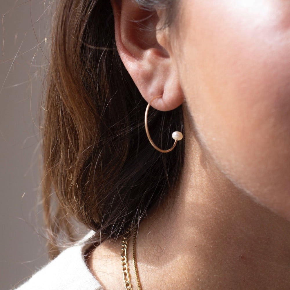 model wearing 14k gold fill wire hoop earrings with pearls on the ends 