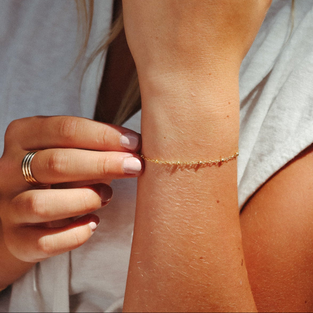model wearing 14k gold fill beaded chain bracelet in the sunlight