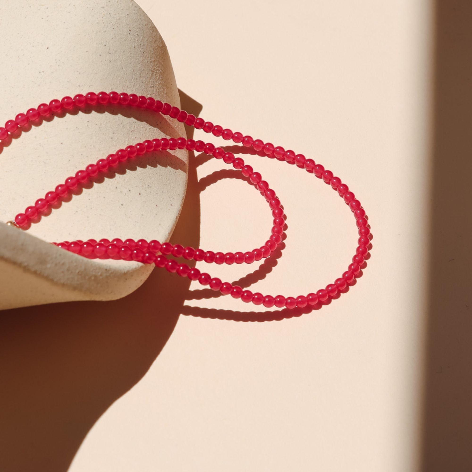 beaded necklace with smooth ruby stones on a light dish