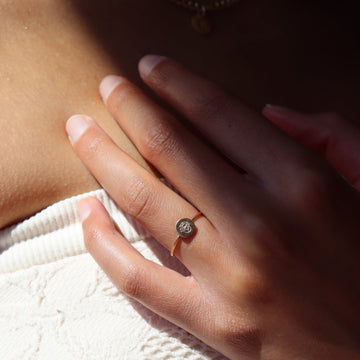 A woman wearing a ring band with a small 14k gold filled disc that's stamped with a birth flower.