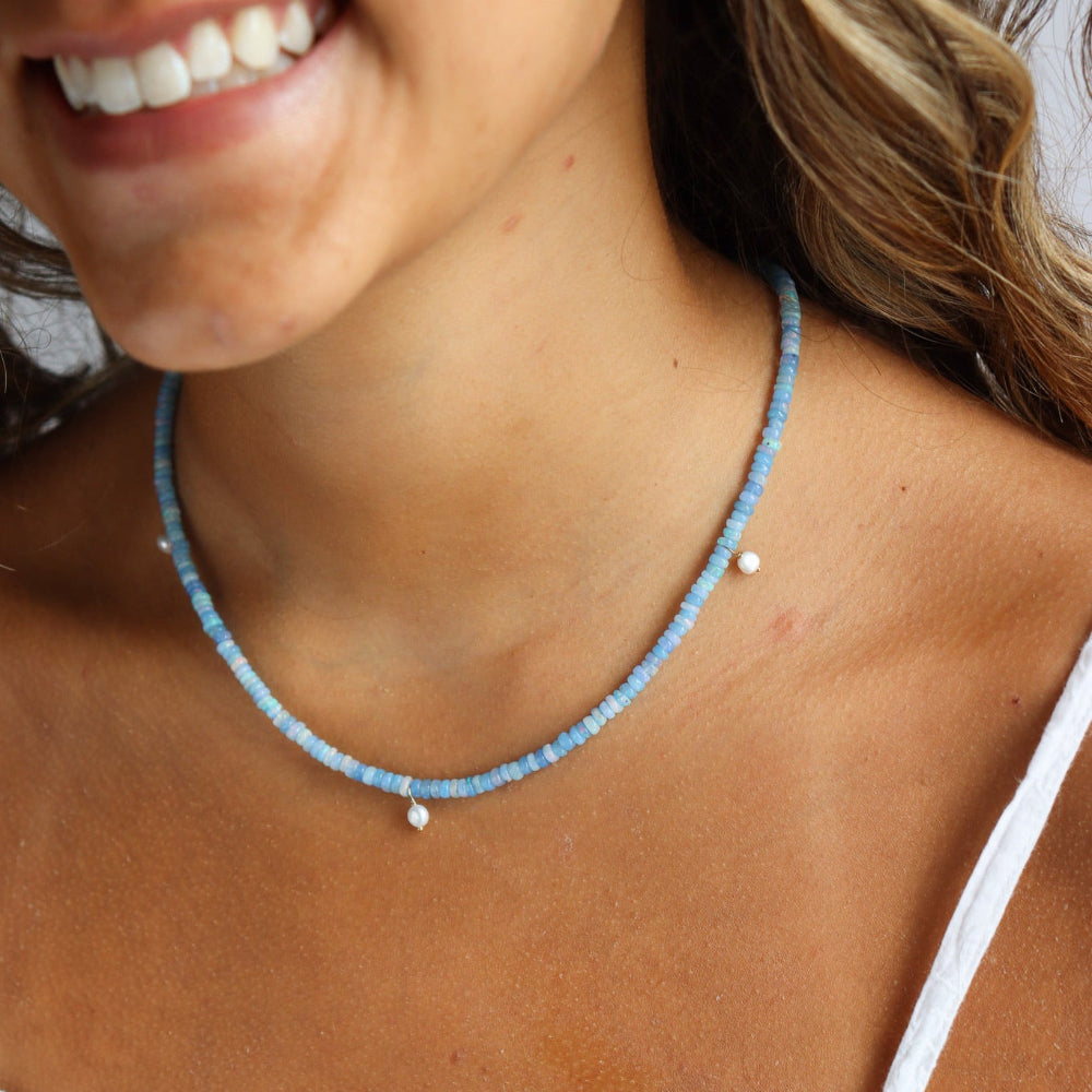 Model wearing a 14k gold fill fully beaded necklace featuring blue opal gemstones and 6 freshwater pearls.