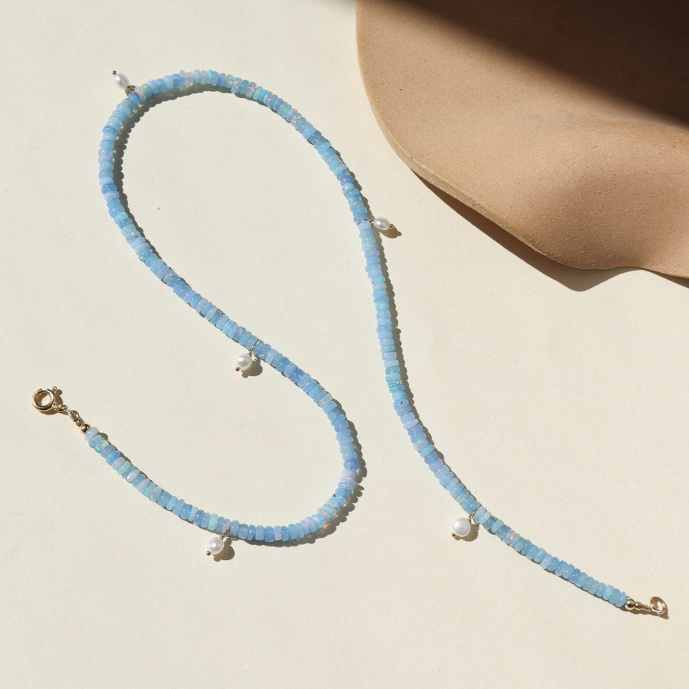A 14k gold fill fully beaded necklace featuring blue opal gemstones and 6 small freshwater pearls. The necklace is displayed on a cream back drop. 