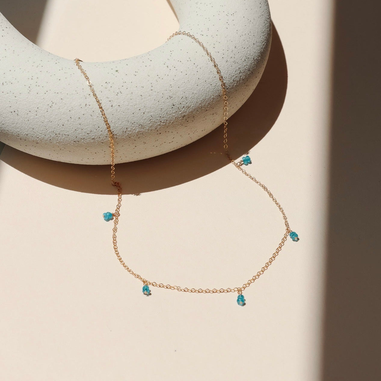 14k gold fill delicate chain necklace with gemstone charms in the sunlight