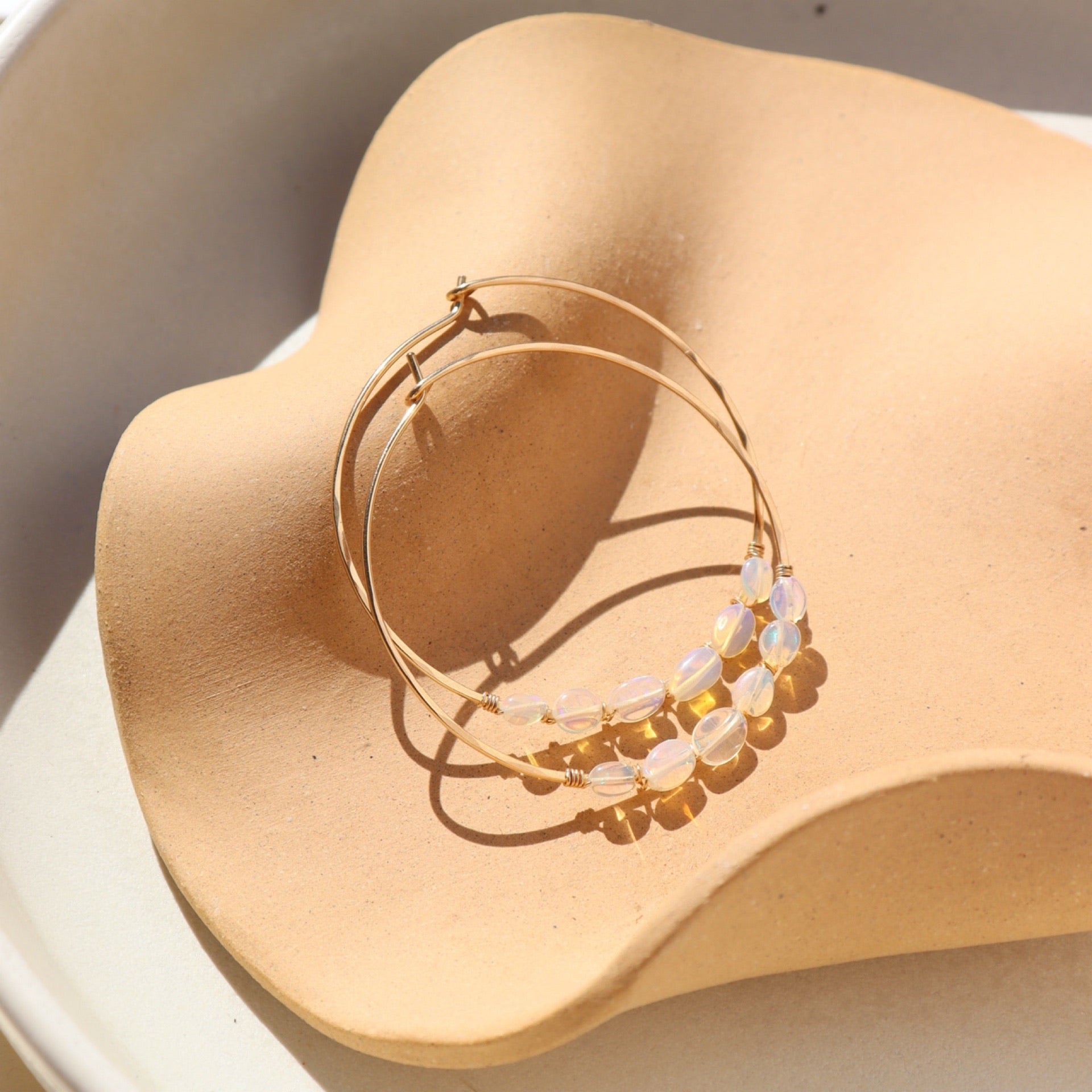 14k gold fill hoop earrings with opals wire wrapped on a light dish