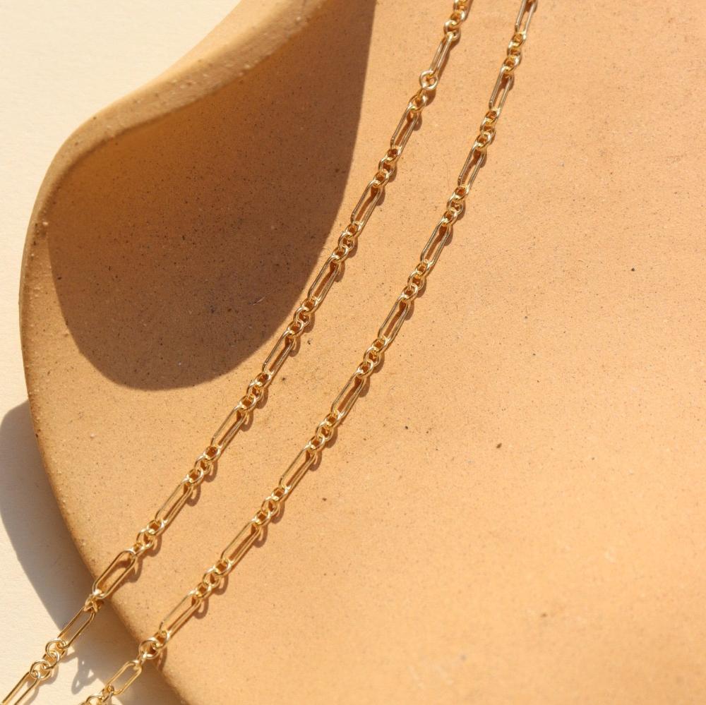 14k gold fill Callie chain laid on a tan plate