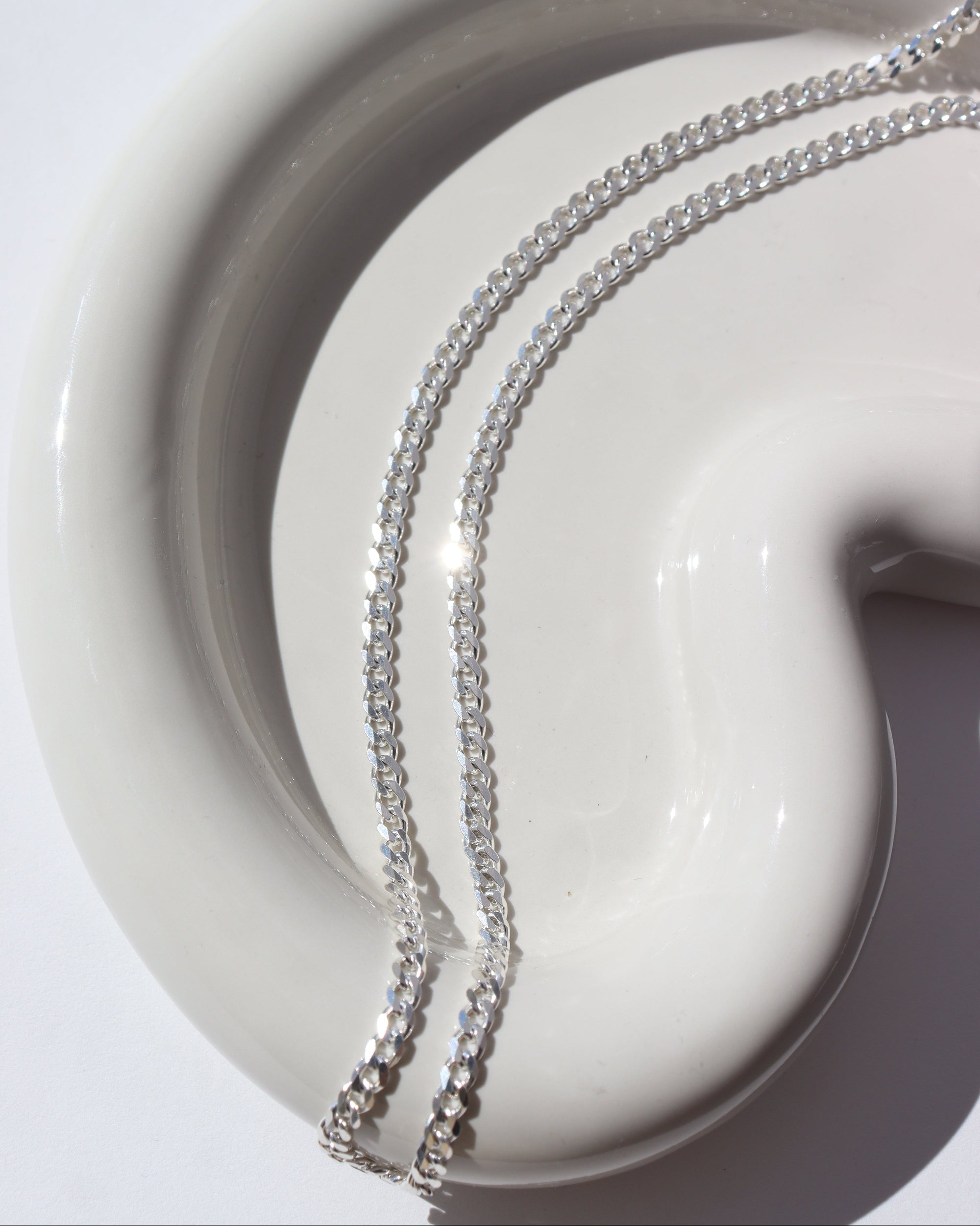 sterling silver curb chain necklace on a light dish in the sunshine