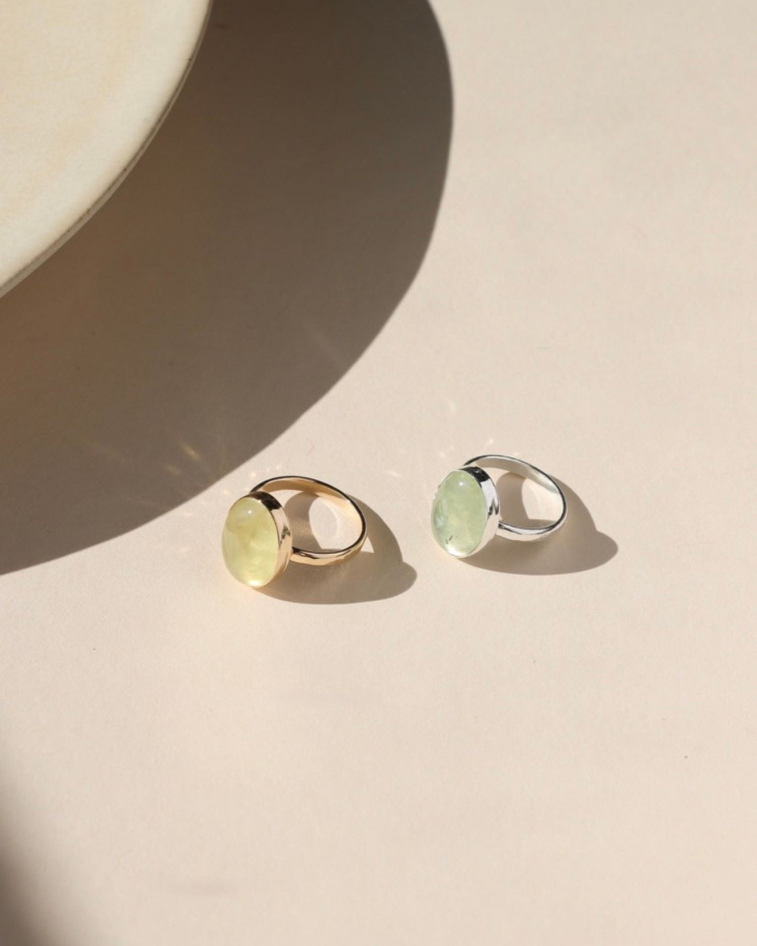 14k gold fill and sterling silver bezel rings with prehnite stones in the sunlight