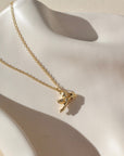 14k gold fill necklace with a thin standard chain with a cupid gold charm at the end of chain. Necklace is displayed on a white dish. 