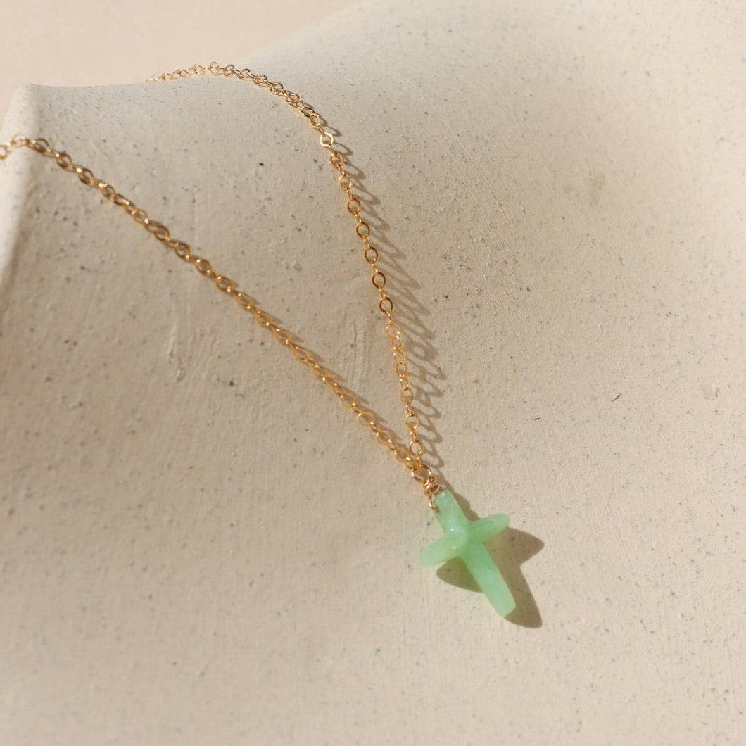 14k gold fill delicate chain necklace with Chrysophrase cross charm on a light dish