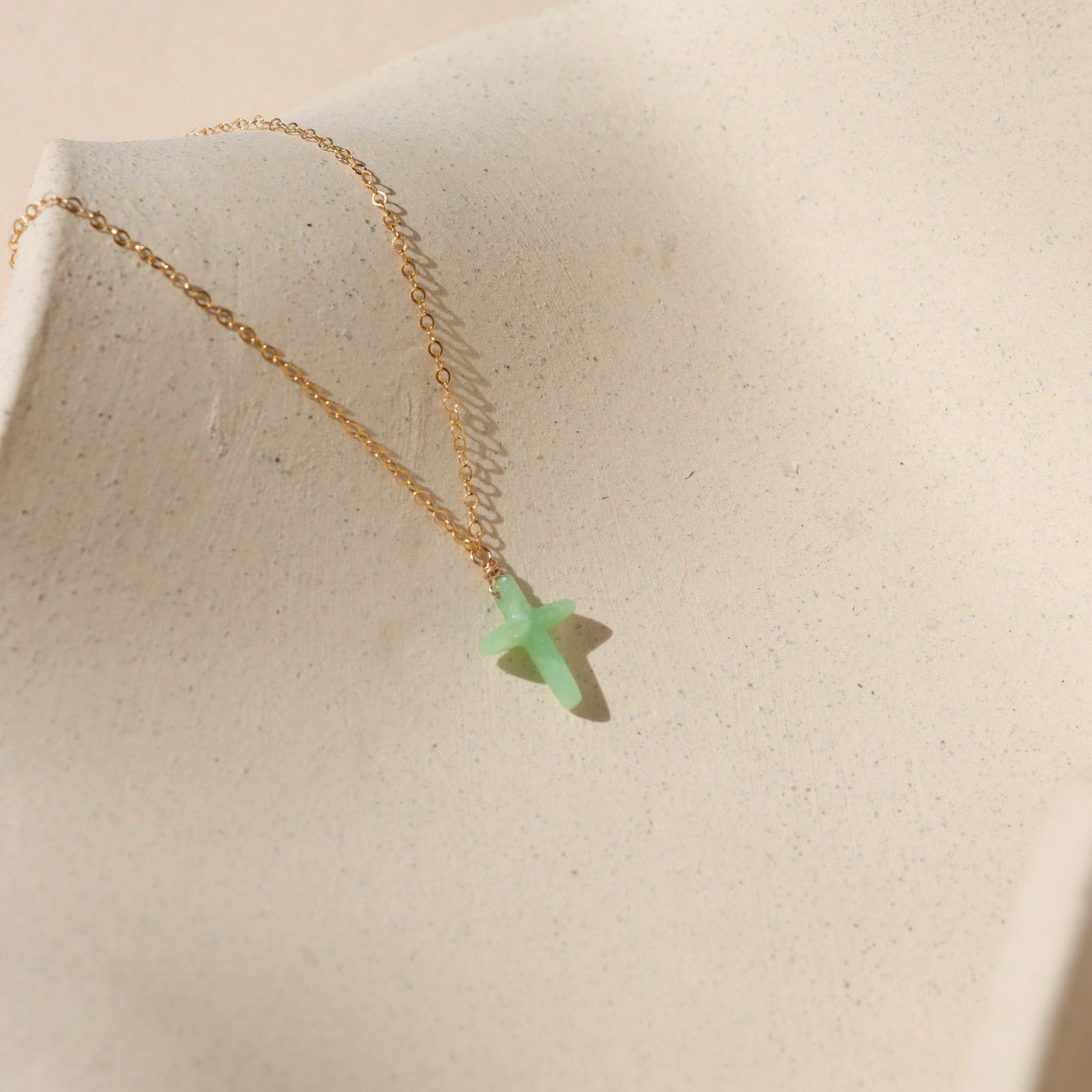 14k gold fill delicate chain necklace with Chrysophrase cross charm on a light dish