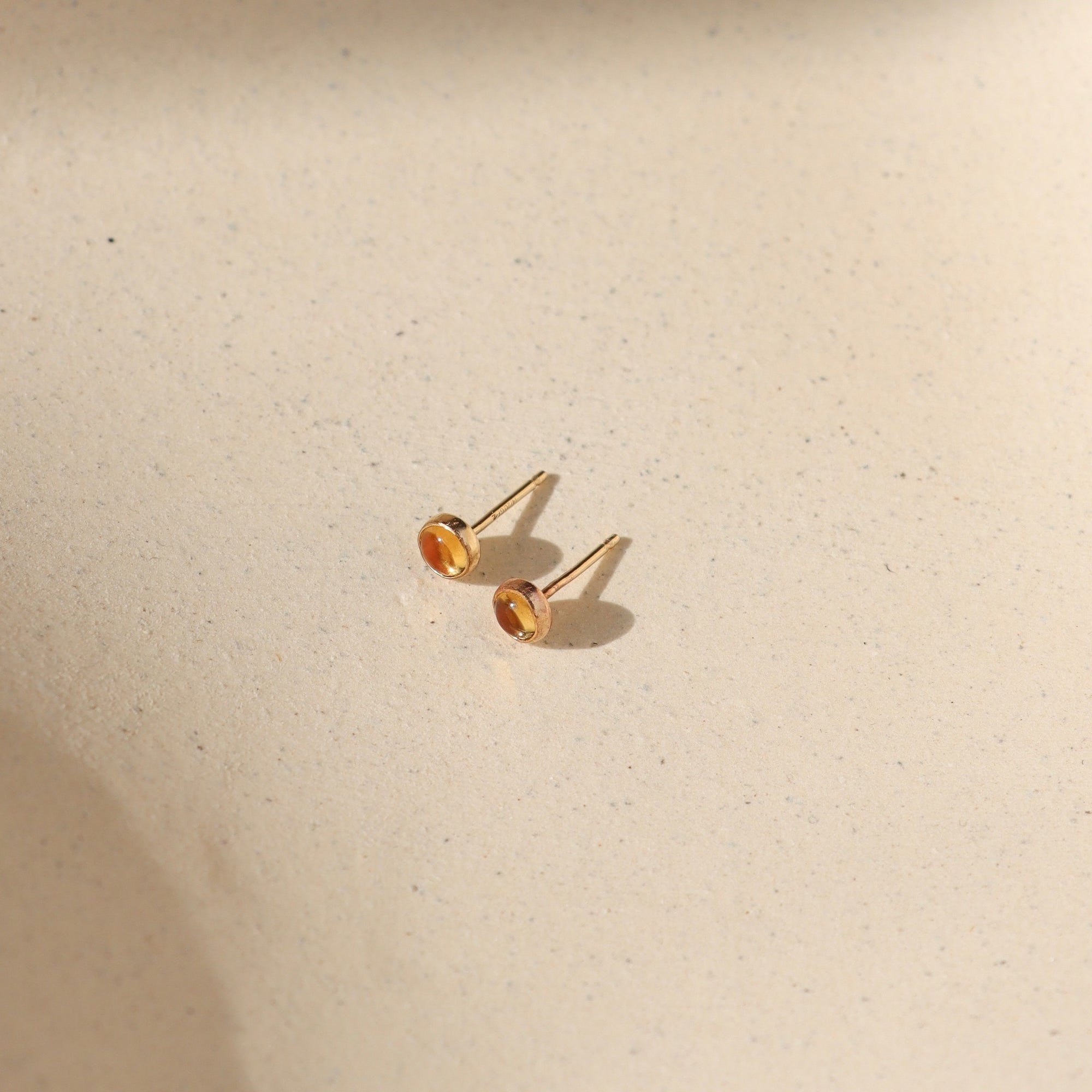 14k gold fill bezel ear posts with 4mm citrine stone on a light background