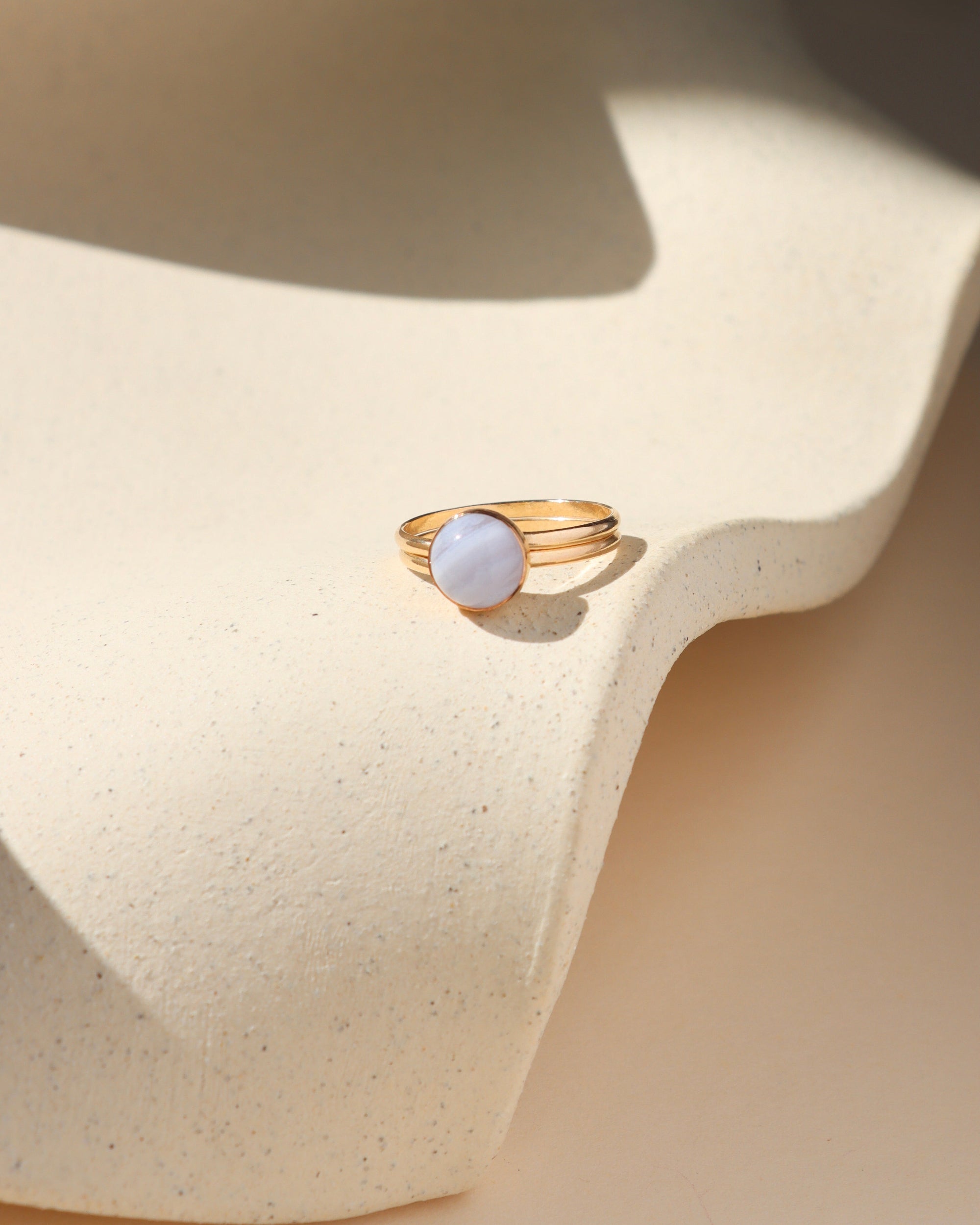 14k gold fill double band bezel ring with round blue lace agate stone on a light dish