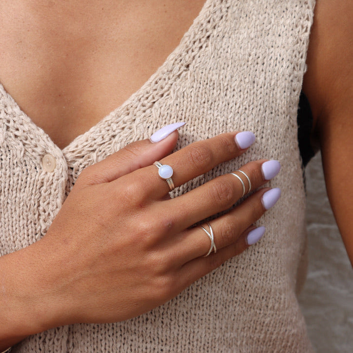 model wearing sterling silver ring with a round blue lace agate stone paired with other sterling silver rings