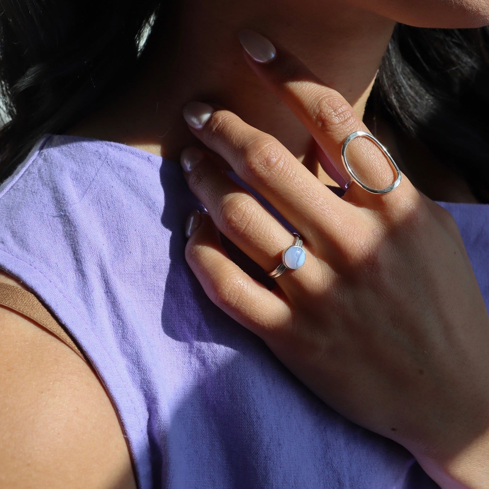 model wearing sterling silver halo ring and sterling silver ring with round blue lace agate stone
