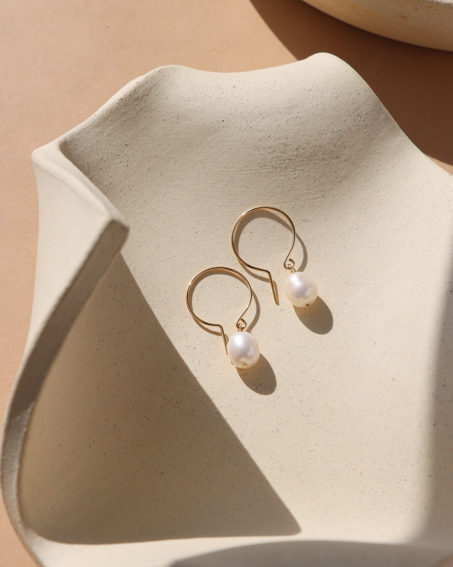 14k gold fill shaped earrings with fresh water pearls on a light dish