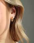 Model wearing Croissant Huggie Hoops, worn with the classic studs. 