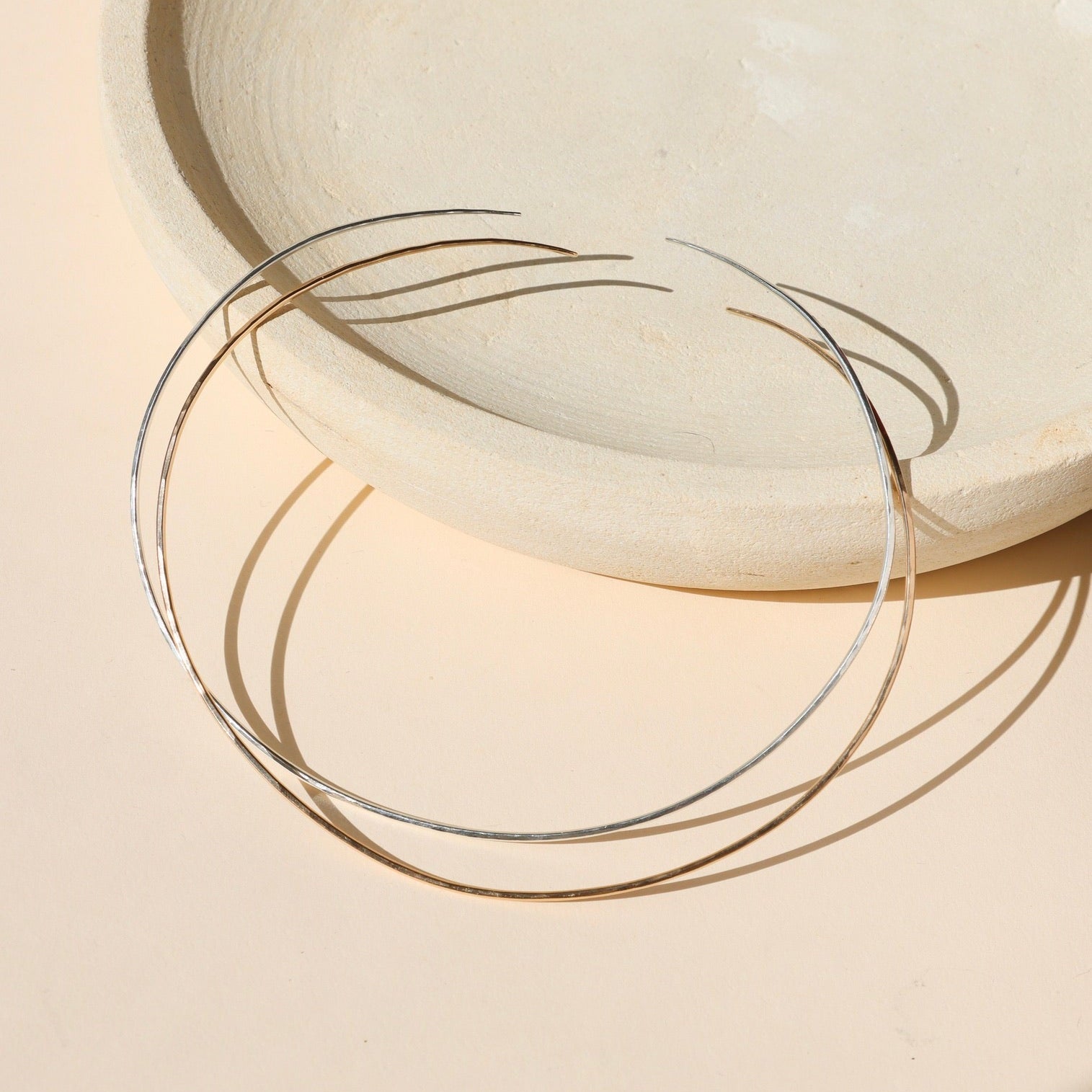 14k gold fill and sterling silver collarbone wire necklaces on a light dish 