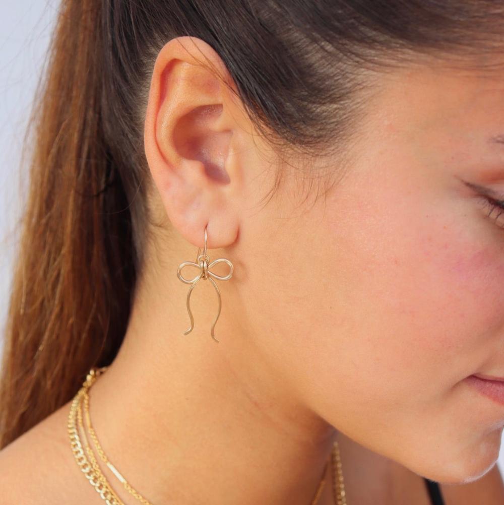 model wearing 14k gold fill hand shaped bow earrings on french ear wire 