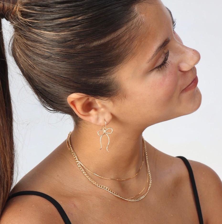 model wearing sterling silver hand shaped bow earrings on french ear wire 