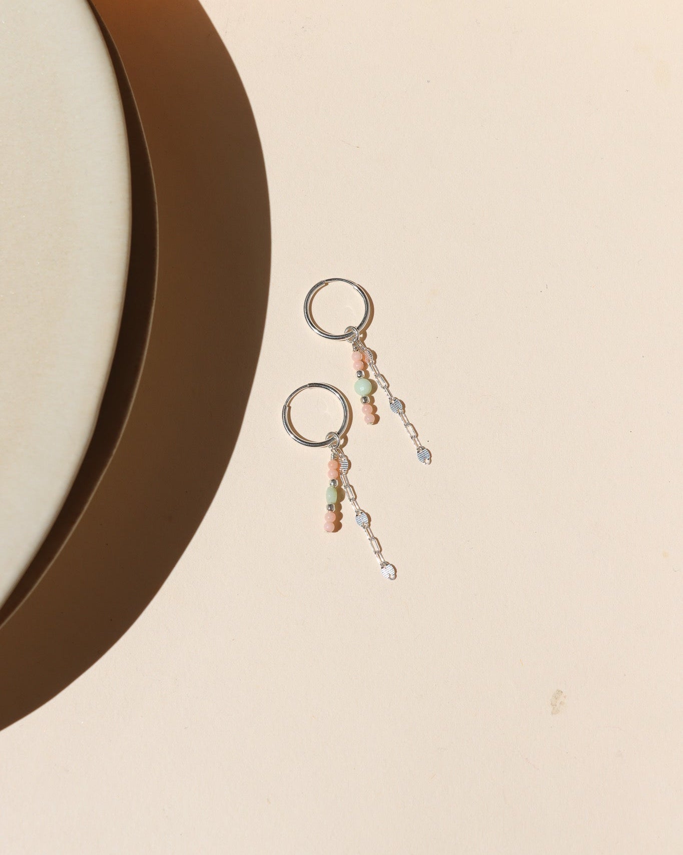 sterling silver hoops with sparkly chain and chrysoprase and coral beads on a light surface