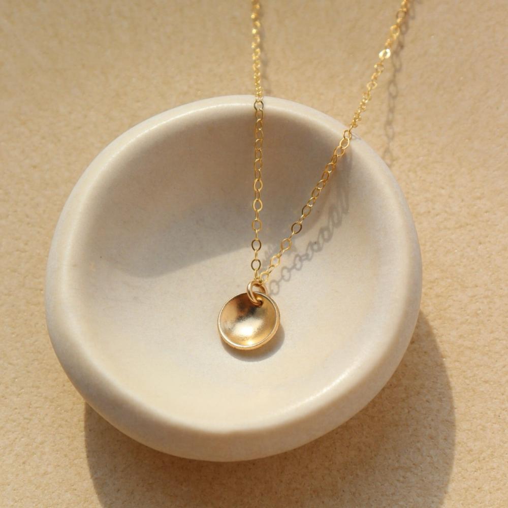 A small concave disc on a simple chain in 14k gold fill by token jewelry