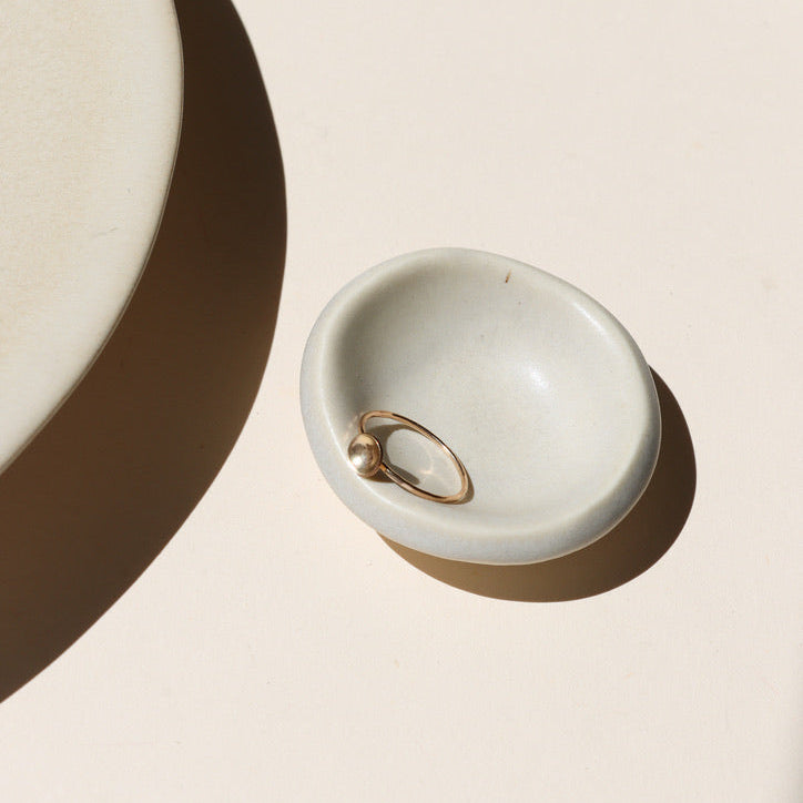 14k gold fill delicate band ring with curved disc on a light dish