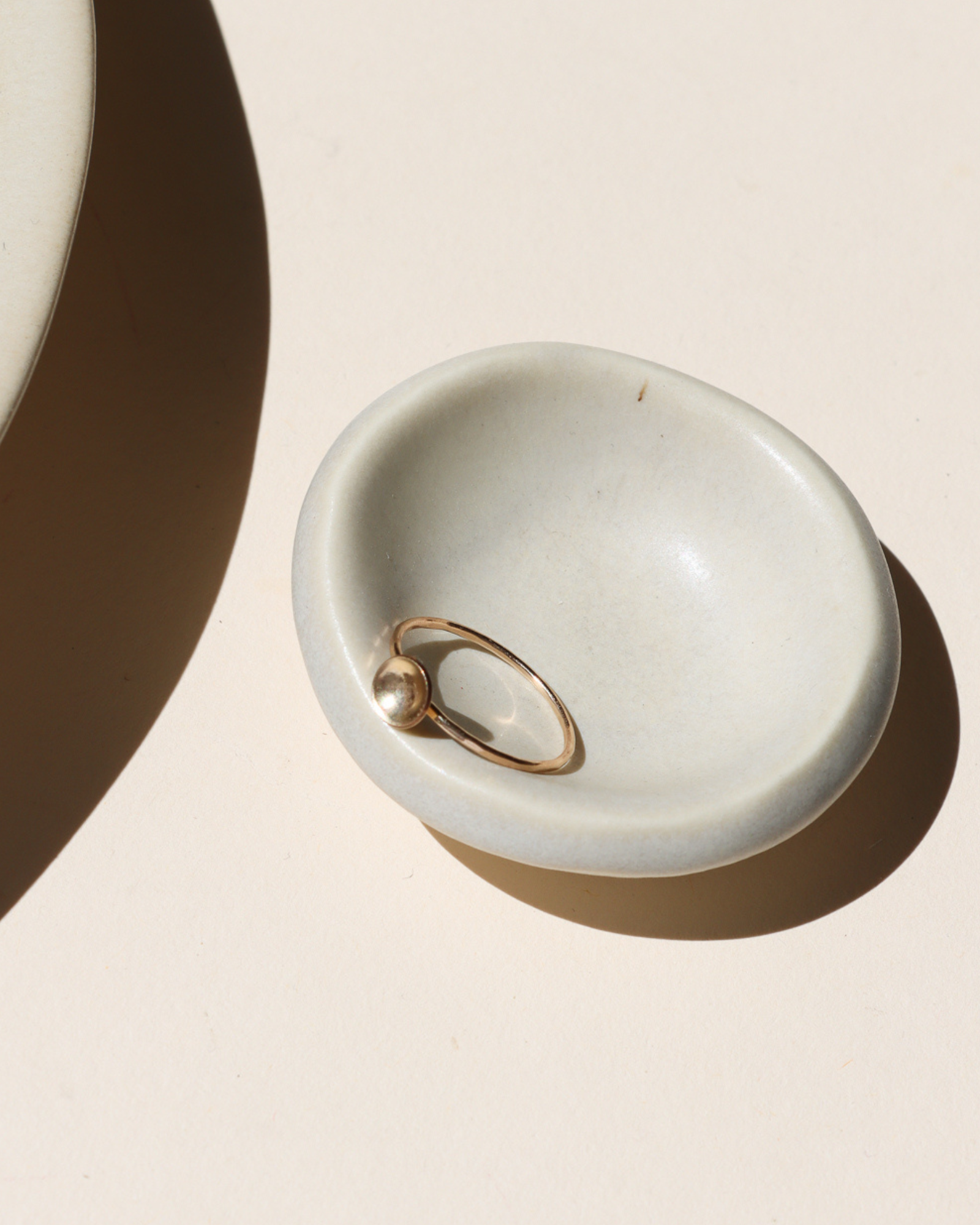 14k gold fill delicate band ring with curved disc on a light dish
