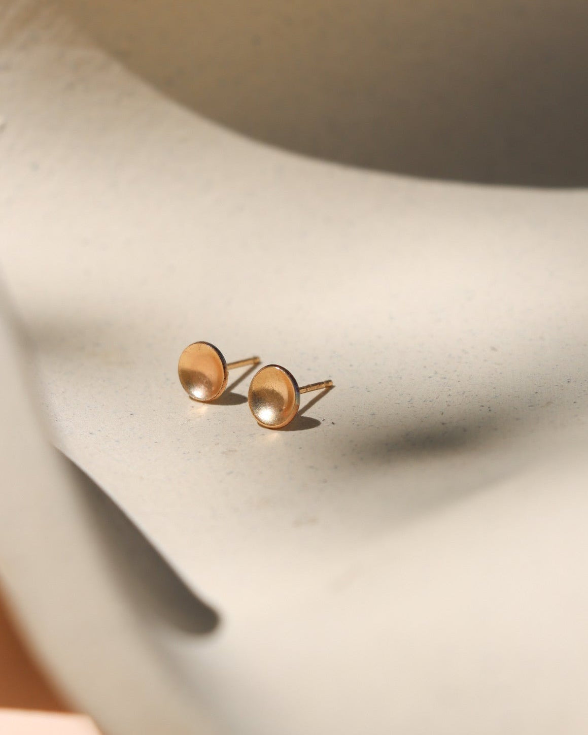 14k gold fill domed circle studs on a light dish