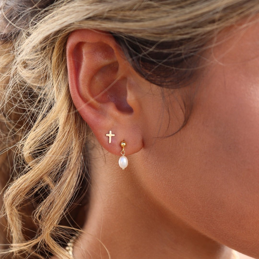 model wearing 14k gold fill cross stud earrings with studs with pearl drops