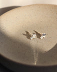 Sterling Silver cross stud earrings. Sitting on a gray plate sitting in the sunlight.