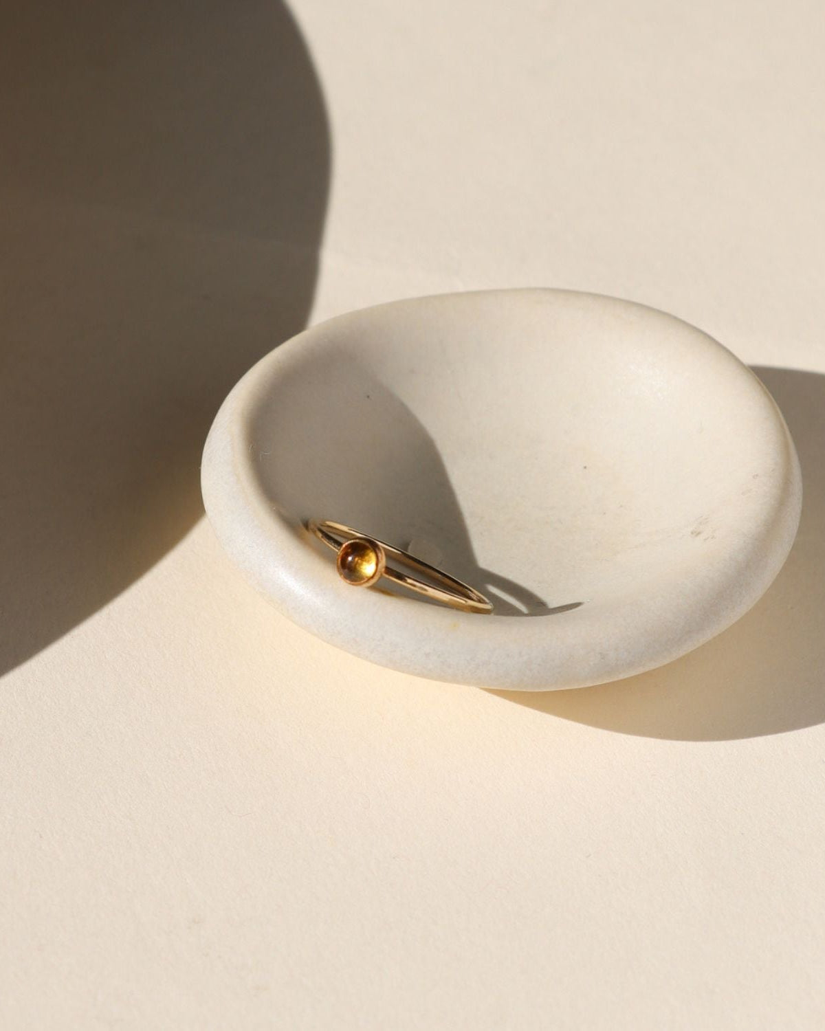 14k gold fill ring with round citrine stone on a light bowl