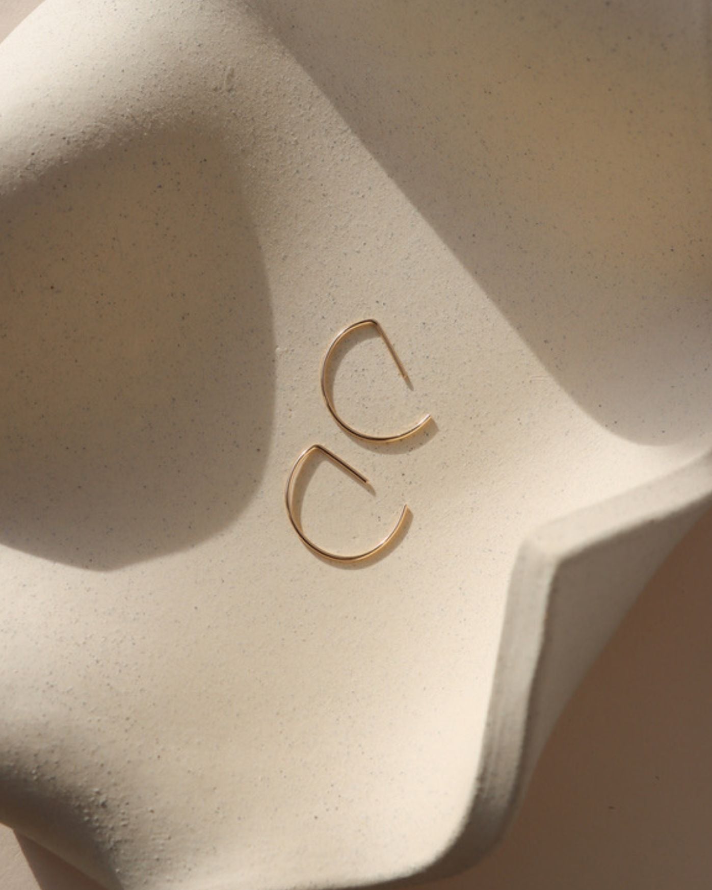 14k gold fill half circle shaped threader earrings on a light dish