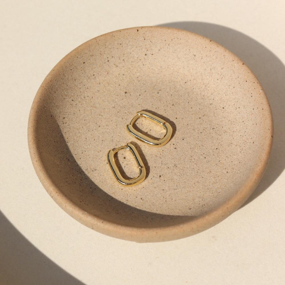 14k gold filled small rectangular huggie hoop earring with clasp closure on a jewelry dish