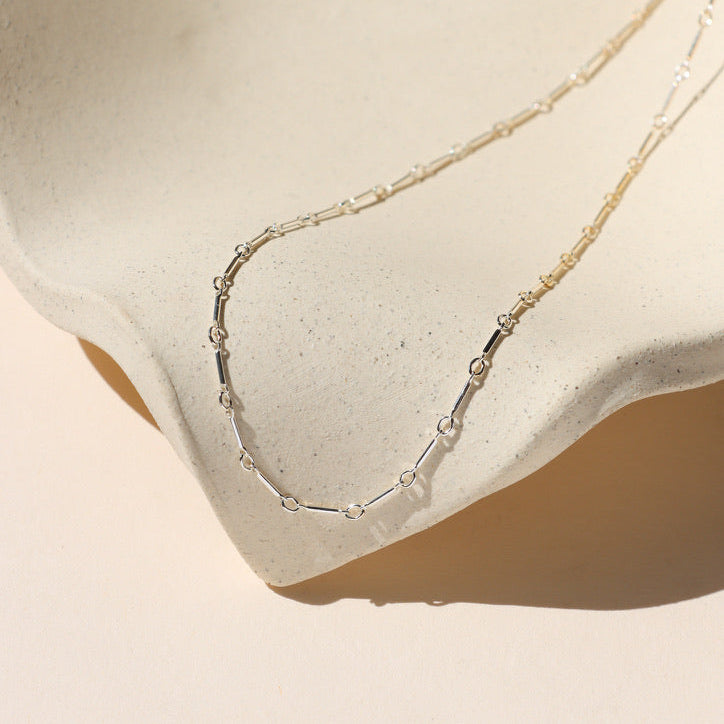 bar and loop chain in sterling silver on a light dish