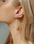 Model wearing 14k gold fill Tiny Moon Studs layered with another pair of token jewelry earrings.