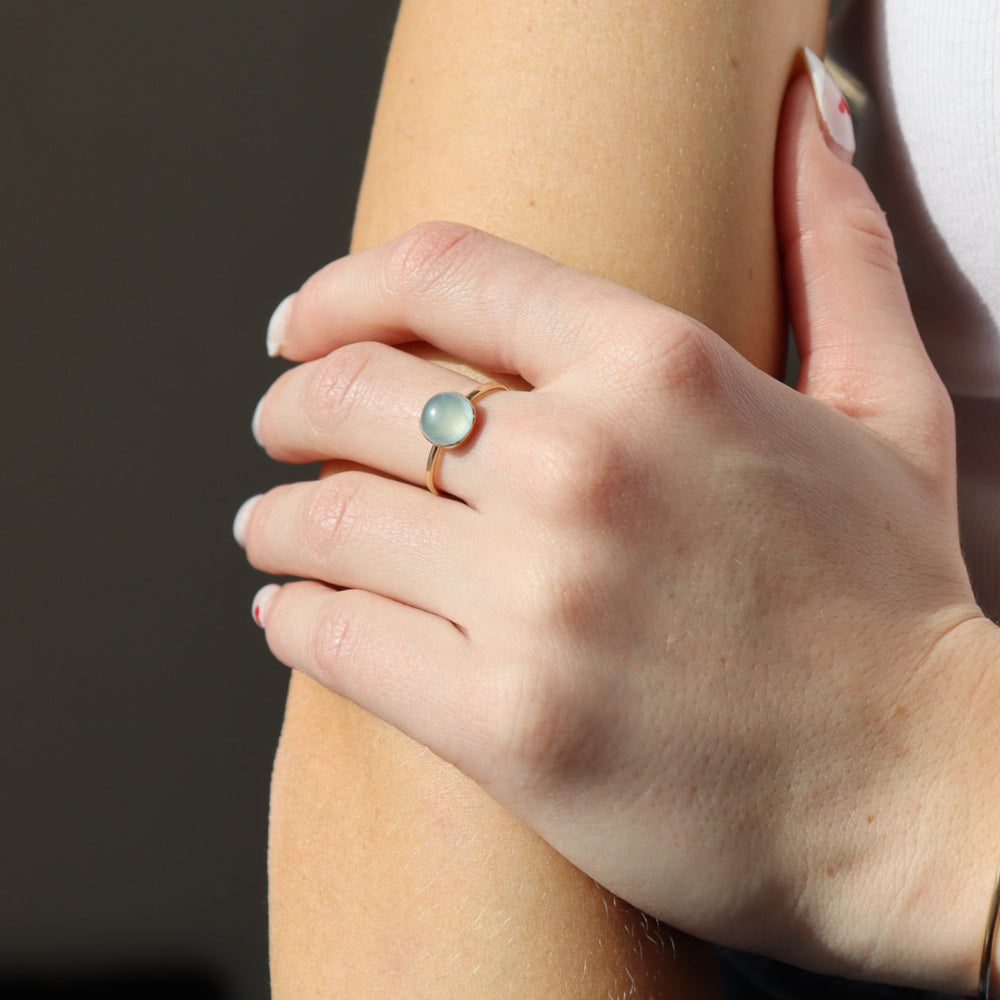 Model wearing a 14k gold fill hammered gold band with a 8mm aquamarine gemstone set in a gold bezel.  