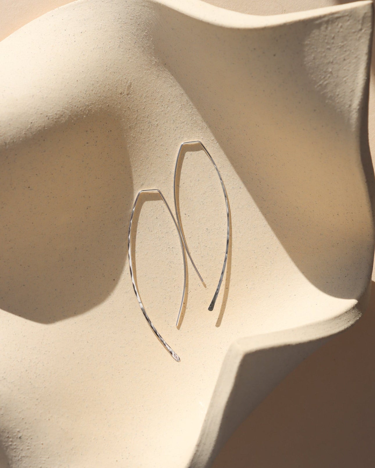 sterling silver hammered shaped threader earrings on a light dish